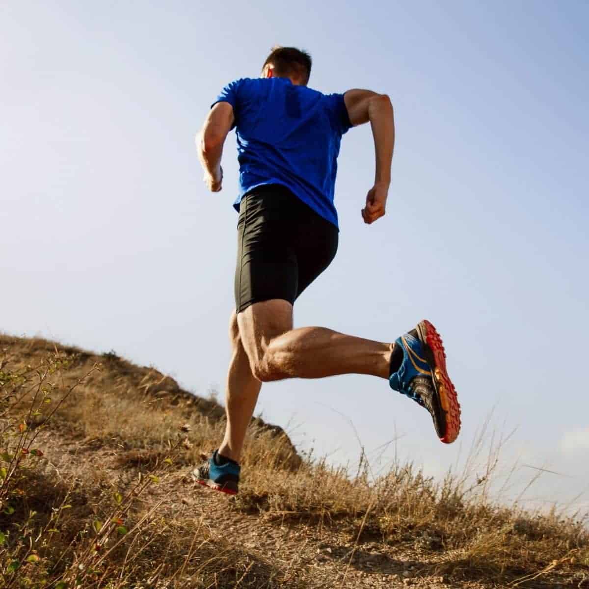 Person running up a grass hill.