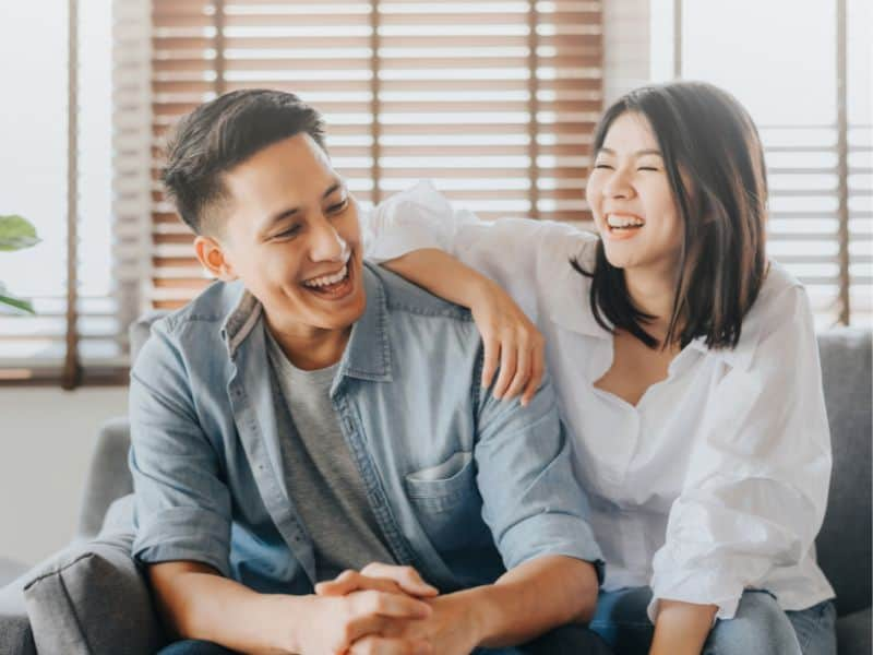 Couple sitting on a couch and laughing.