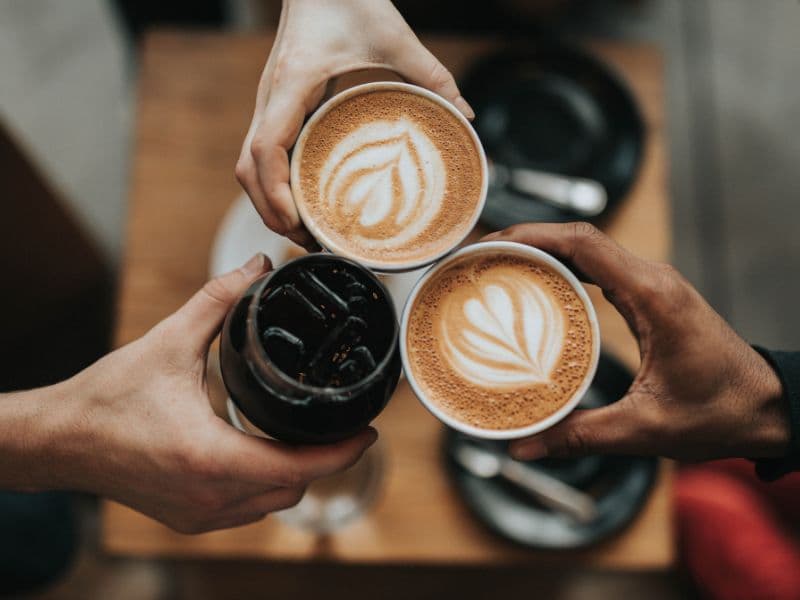 Three hands holding cups of coffee.