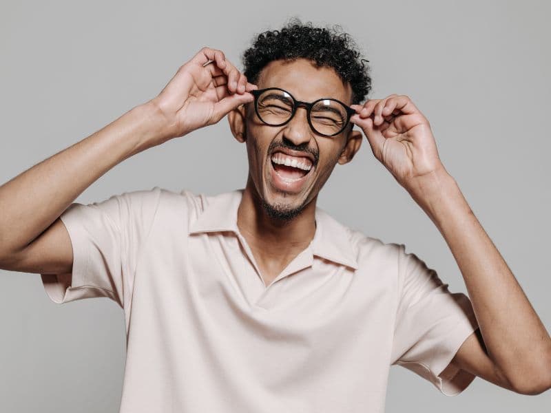 Person wearing glasses and laughing indoors.