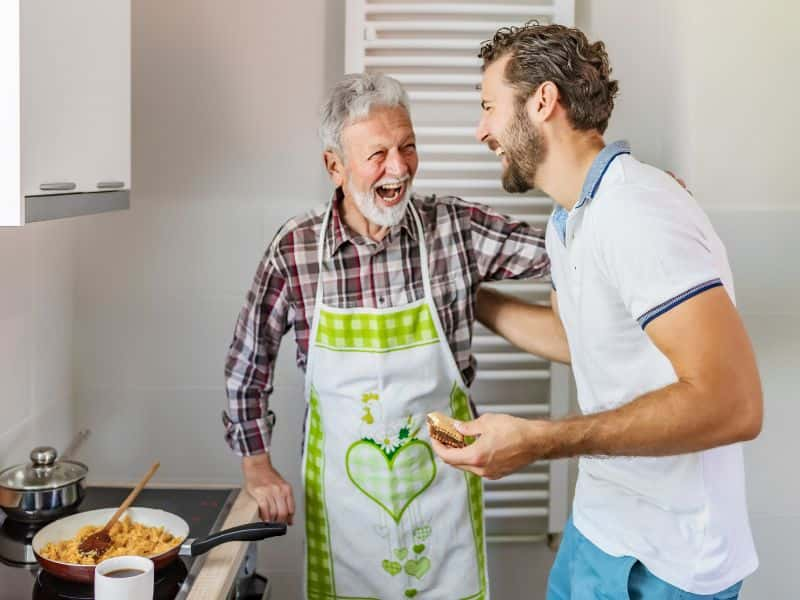 Two men cooking and laughing in the kitchen.